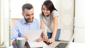 Smiling couple reviewing documents at home, representing individuals researching Colorado Medicaid income limits and eligibility requirements.