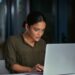 Woman focused on laptop screen at night, researching Colorado open enrollment options after missing the deadline.