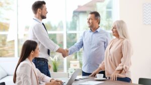 Colorado health insurance agents meeting with clients in a bright office setting, shaking hands and discussing insurance plans.