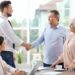 Colorado health insurance agents meeting with clients in a bright office setting, shaking hands and discussing insurance plans.