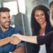 Smiling professionals shaking hands in an office setting, representing a positive meeting with Colorado health insurance brokers.