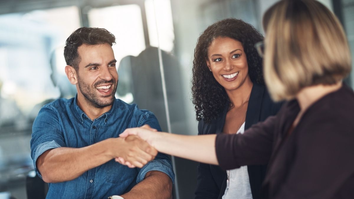 Smiling professionals shaking hands in an office setting, representing a positive meeting with Colorado health insurance brokers.