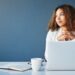 Thoughtful woman sitting at desk with laptop, symbolizing planning and decision-making about Colorado Medicaid inheritance and asset protection.