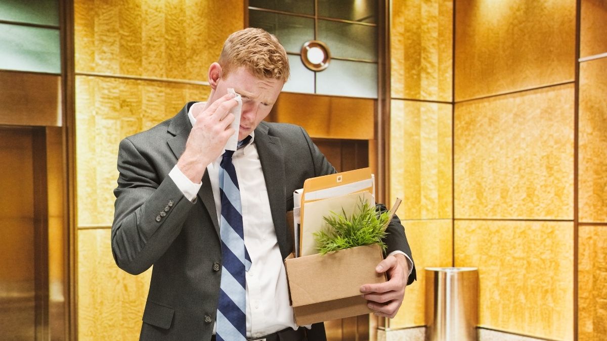 Upset man leaving his job with a box of personal belongings, representing the question how long do you have health insurance after leaving a job.