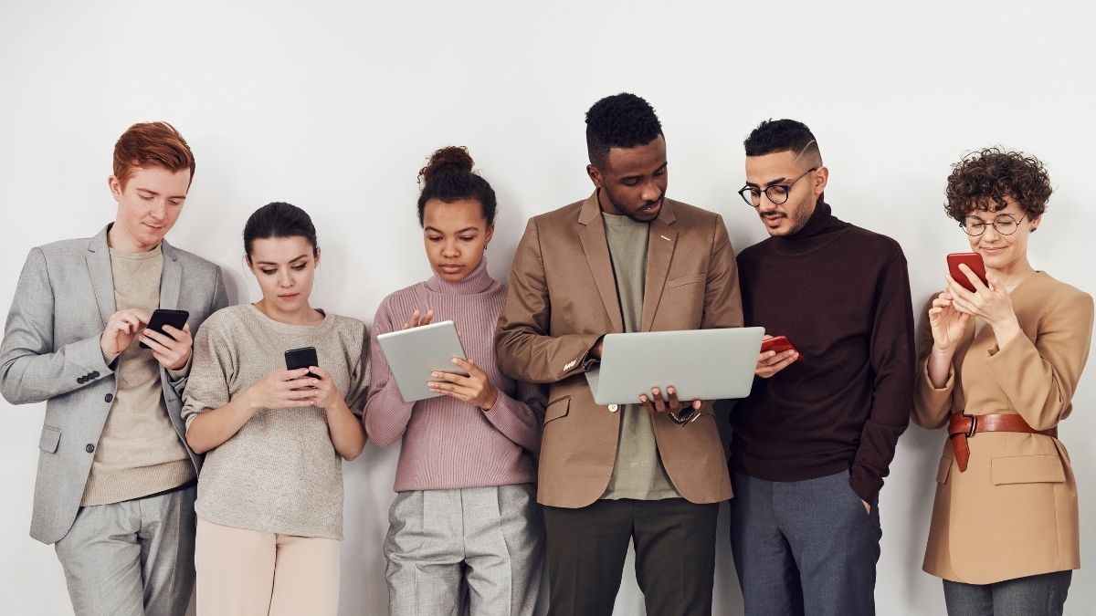 Diverse group of professionals using laptops and smartphones, representing how group insurance differs from individual insurance.