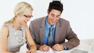 Two professionals smiling during a meeting, representing a positive client experience for a blog discussing Kaiser Permanente in Colorado.
